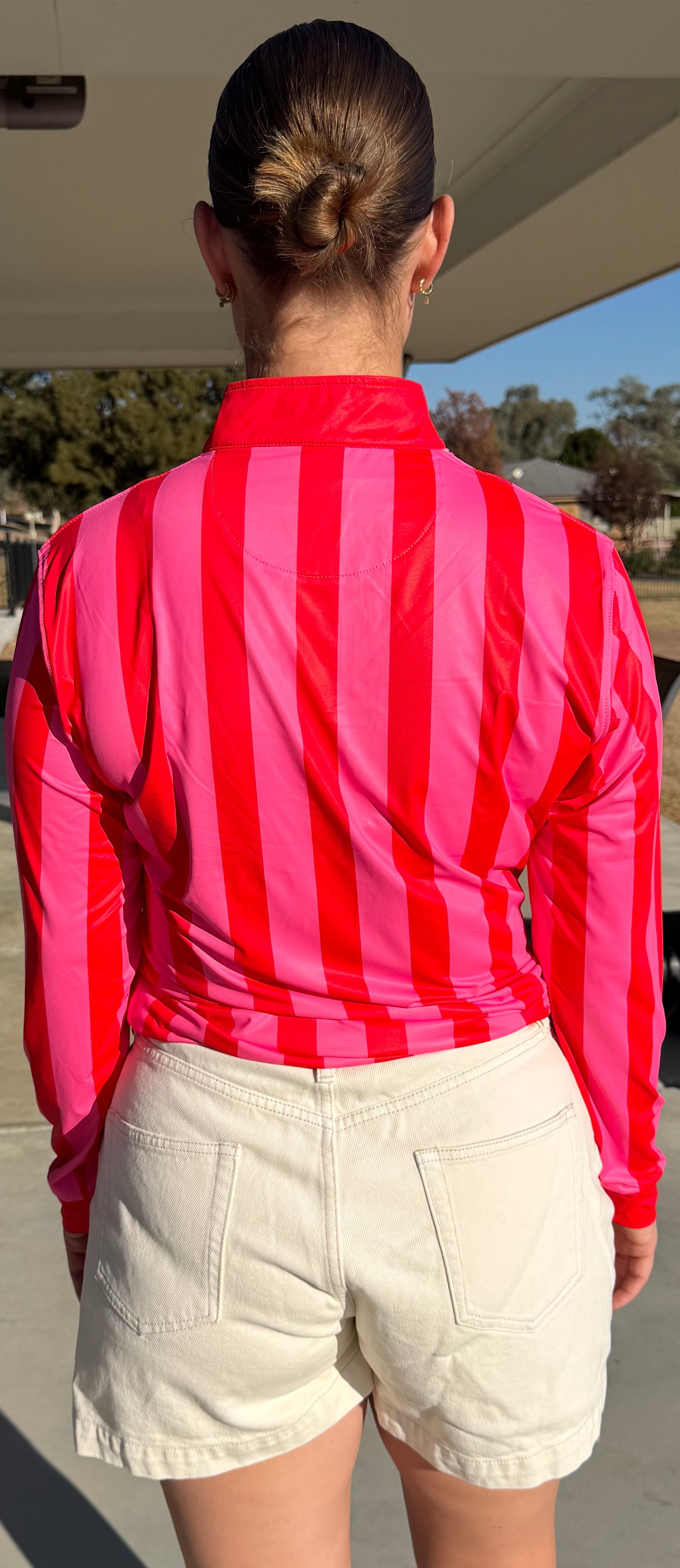 Women wearing a red and white UPF 50+  striped shirt and beige shorts 